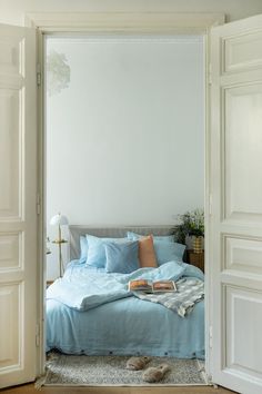 an open door leading to a bed with blue sheets and pillows on top of it