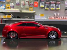 a red toy car is parked on the floor in front of a store display case