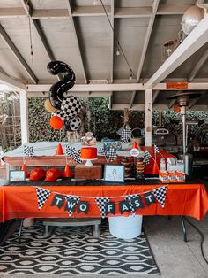 an orange and black party table set up for a race car themed birthday