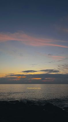 the sun is setting over the ocean with some clouds in the sky and an inscription on the water