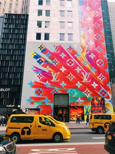 a very tall building with many different colored designs on it's side and cars parked in front