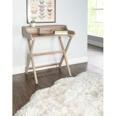 a small wooden desk sitting on top of a hard wood floor next to a white rug