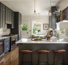 a kitchen with three stools next to an island