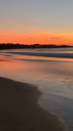 the sun is setting over the water at the beach