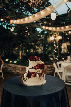 a wedding cake sitting on top of a table under a chandelier with lights