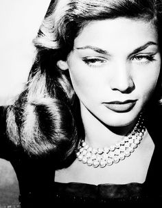 a black and white photo of a woman wearing pearls