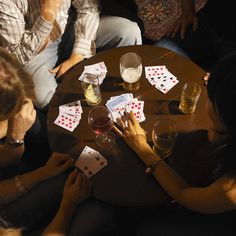 people sitting around a table playing cards and drinking wine