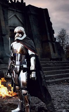 a man dressed in armor standing next to a fire