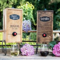 three wine glasses sitting on top of a table next to two boxes with flowers in them