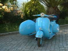 an old blue scooter is parked on the sidewalk