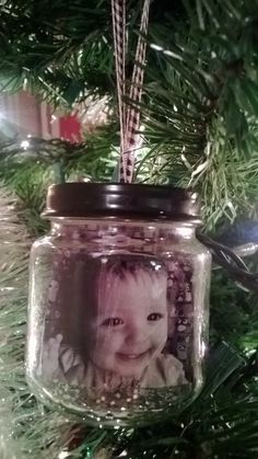 a christmas ornament hanging from a tree with a baby's photo on it