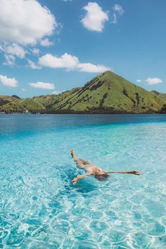 a person floating in the water on top of a body of water with mountains in the background