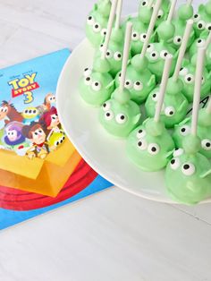 there are many green candies with googly eyes on them and a toy story book in the background