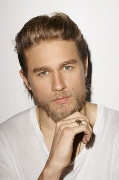 a man with a ring on his finger looking at the camera while wearing a white t - shirt