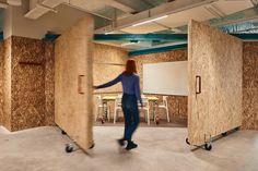 a woman is moving around in a room with plywood panels on the walls and floor