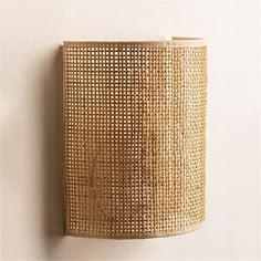 a wall lamp made out of woven material on the side of a white wall,