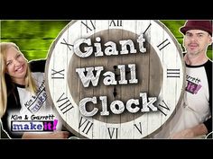 a man and woman standing in front of a giant clock with the words giant wall clock on it