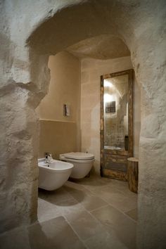 two white toilets sitting next to each other in a bathroom under a doorway with a wooden door