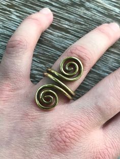 a person's hand with a gold ring on top of their finger and two spiral rings in the middle