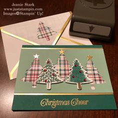 a christmas card with three trees on it and a stamping machine next to it