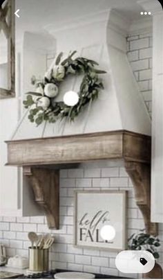 a white kitchen with a wreath on the stove top above it's range hood