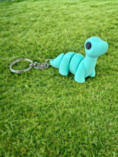 a small blue toy sitting on top of a green grass covered field next to a metal keychain