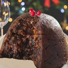 a piece of chocolate cake on a plate next to a wine glass and christmas tree