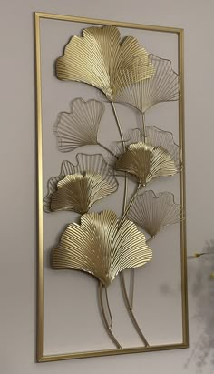 a metal art piece with gold leaves on the back and sides, hanging on a wall