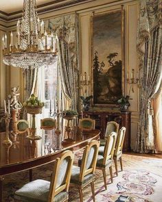 an elegant dining room with chandelier, chairs and paintings on the wall behind it