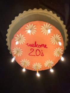 a cake with the words welcome 20's on it and some lights around it