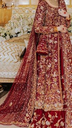 a woman in a red and gold bridal gown standing next to a table with flowers