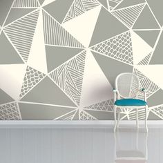 a chair sitting in front of a wall with an artistic design on the wall behind it