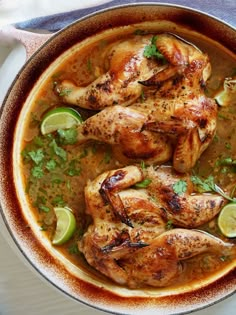 some chicken is in a pot with garnishes and limes on the side