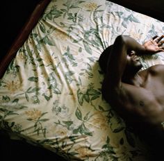 a shirtless man laying on top of a bed