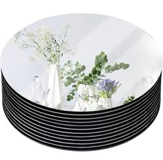 black and white plates stacked on top of each other with flowers in vases next to them