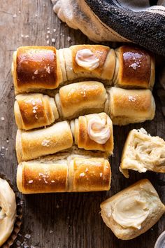 rolls with cream cheese spread on them sitting on a wooden table next to other breads