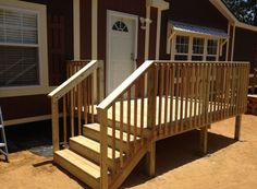 a wooden porch with steps leading to a door and windows on the side of a house