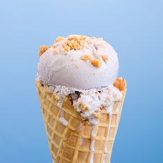 an ice cream cone with white icing and crumbs on top, against a blue background