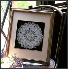 a white doily on a wooden table in front of a window with an open frame