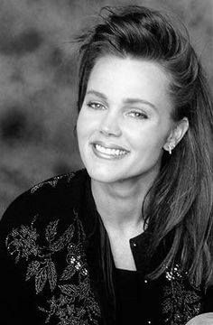 a black and white photo of a woman with long hair smiling at the camera,