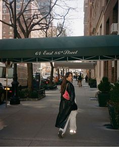 a woman is walking down the sidewalk under an awning