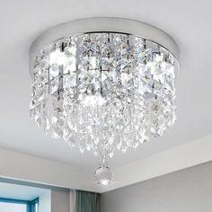 a crystal chandelier hanging from the ceiling in a room with white walls and windows