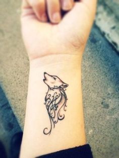 a woman's wrist tattoo with a wolf head on the left side of her arm