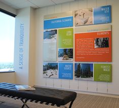 a room with several posters on the wall and a bench in front of it near a window