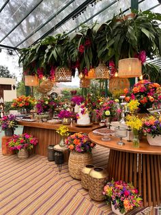 a bunch of flowers that are sitting on a table in a room filled with plants