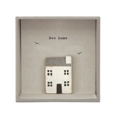 a small white house in a box with the words new home on it's side