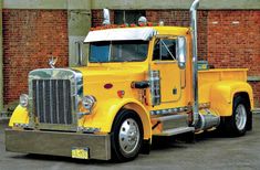 a yellow semi truck parked in front of a brick building