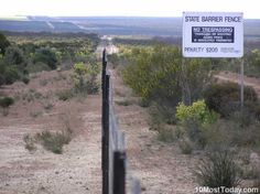 a fenced off road with a sign on it that says state barrier fence no trespassing