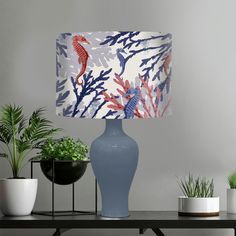 a blue vase sitting on top of a table next to a lamp with red fish