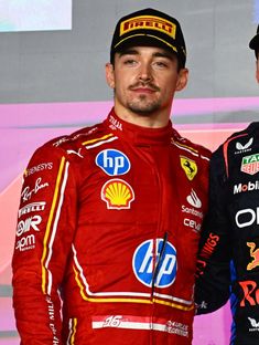 two men standing next to each other in front of a wall